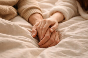 Nahaufnahme von sich sanft berührenden Händen eines Paares als Symbol für Intimität und das Ablegen der Rüstung im Alltag.